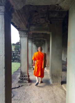 A Buddhist monk walking the aisles of Angkor Wat
